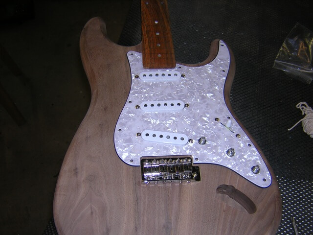 Setting the pickguard and bridge in place to mark where the screw holes should be drilled.