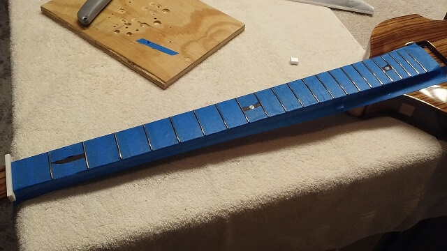 Masking the fretboard in preparation for the fret leveling.