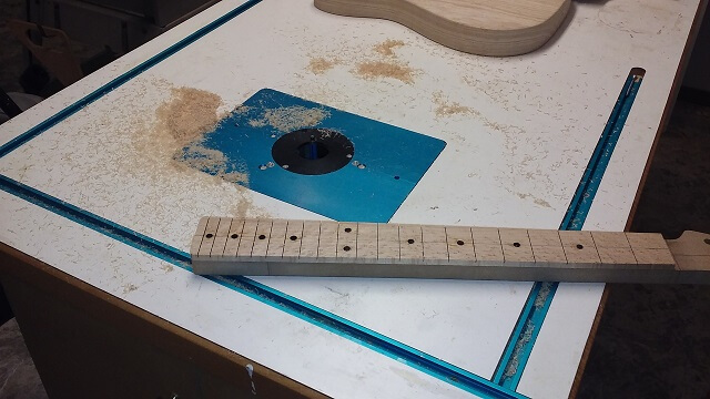 Trimming the fretboard flush with the template.