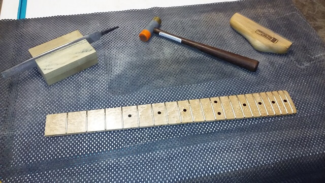 Installing the frets into the fretboard.