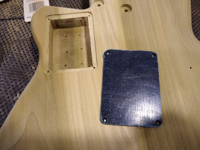 The plastic battery cover cut to shape and drilled.
