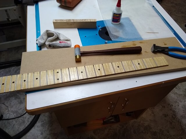 Trimming the ends of the frets flush with the fretboard.