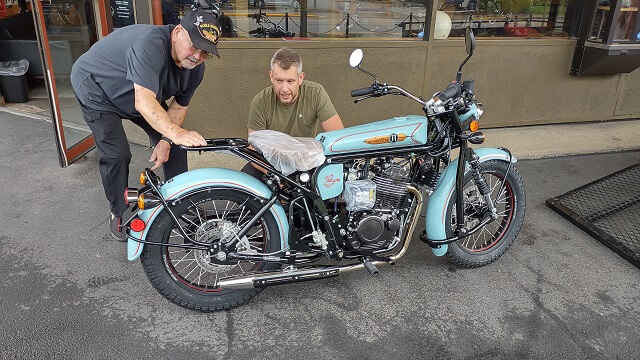 The owner of Janus Motorcycles helping a customer with his new motorcycle.