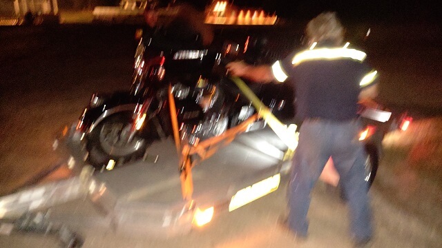 The tow truck driver strapping my motorcycle down in the dark in Dyersville, IA.