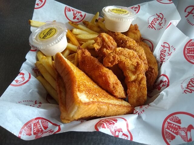 Eating chicken strips, fries and toast at Slim Chickens.