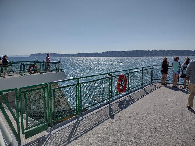 People enjoying the sun deck on top of the ferry.