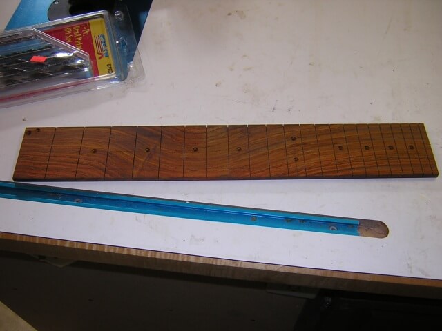 Holes for the dot inlays drilled in the fretboard.