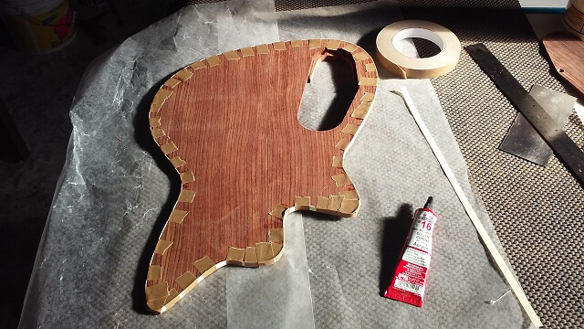 Gluing binding to the back of the guitar.