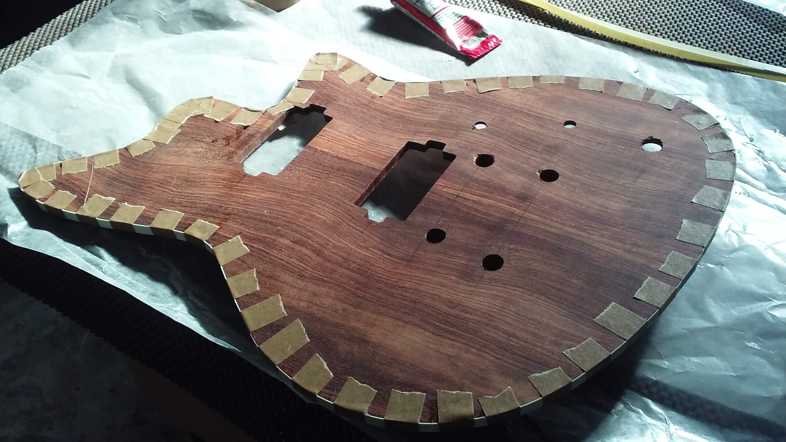 Gluing binding to the front of the guitar.