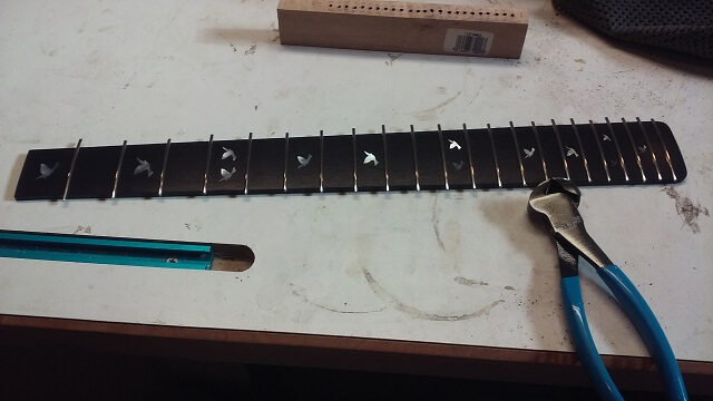 Trimming the frets flush with the fretboard.