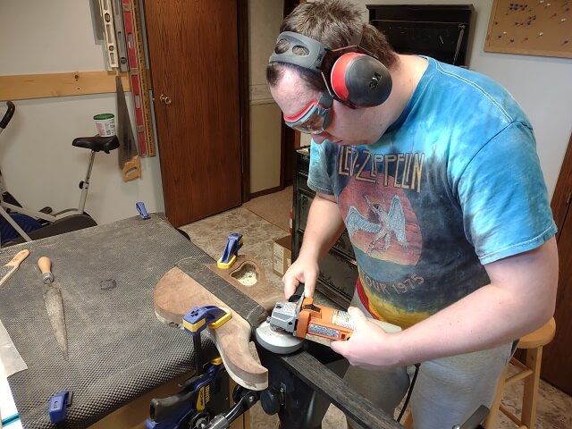 Rough carving the neck heel with a disc sander.