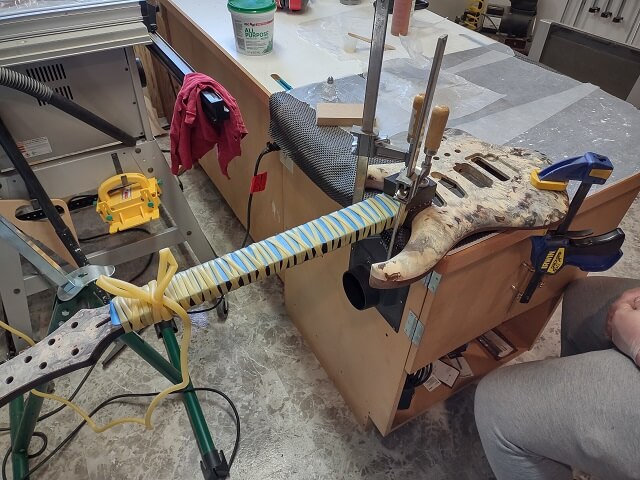 Using surgical tubing to clamp the fretboard in place.
