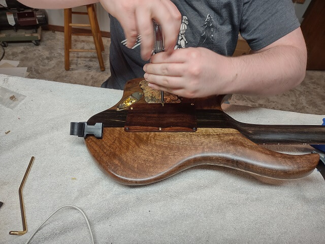 Screwing the tremolo cavity cover in place.