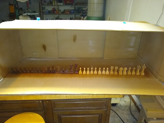 Spraying finish on the chess pieces.